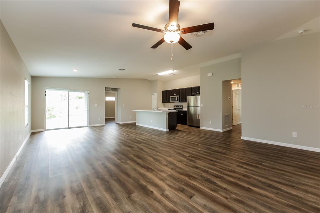 An open-concept living area features wood-look flooring, a ceiling fan, and a kitchen with island — 4208 WALL LANE, NORTH PORT, FL
