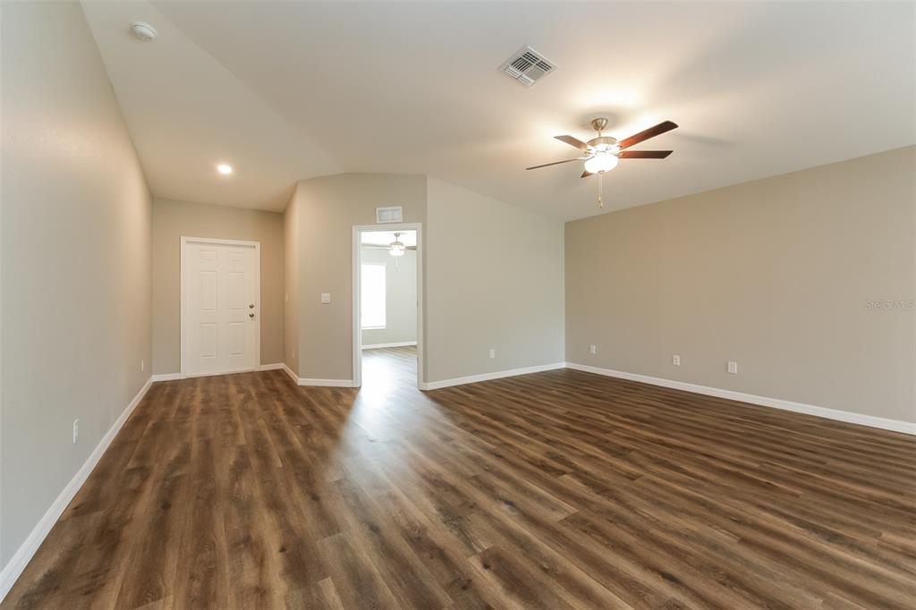 An empty room features wood-look flooring, a ceiling fan, and a doorway leading to another room — 4208 WALL LANE, NORTH PORT, FL
