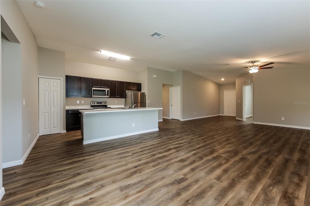 An open-concept kitchen with dark cabinets and a breakfast bar overlooks a spacious living area — 4208 WALL LANE, NORTH PORT, FL