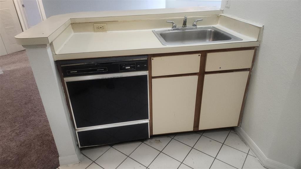 A kitchen area features a stainless steel sink, a black dishwasher, and off-white cabinets — 5713 GATLIN AVENUE UNIT 216, ORLANDO, FL