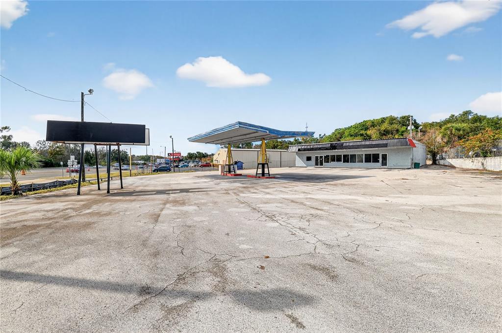 An exterior view of a vacant gas station with a canopy and a paved lot — 1526 US HIGHWAY 441, LEESBURG, FL