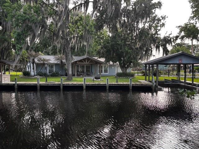 A waterfront house with a wooden dock and a boat slip under large mossy trees — 137 & 135 RIVERSIDE DRIVE, SATSUMA, FL