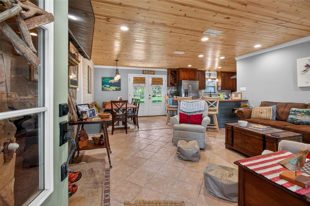 An open-concept living and dining area features tile flooring, a wood-paneled ceiling, and a kitchen — 137 & 135 RIVERSIDE DRIVE, SATSUMA, FL