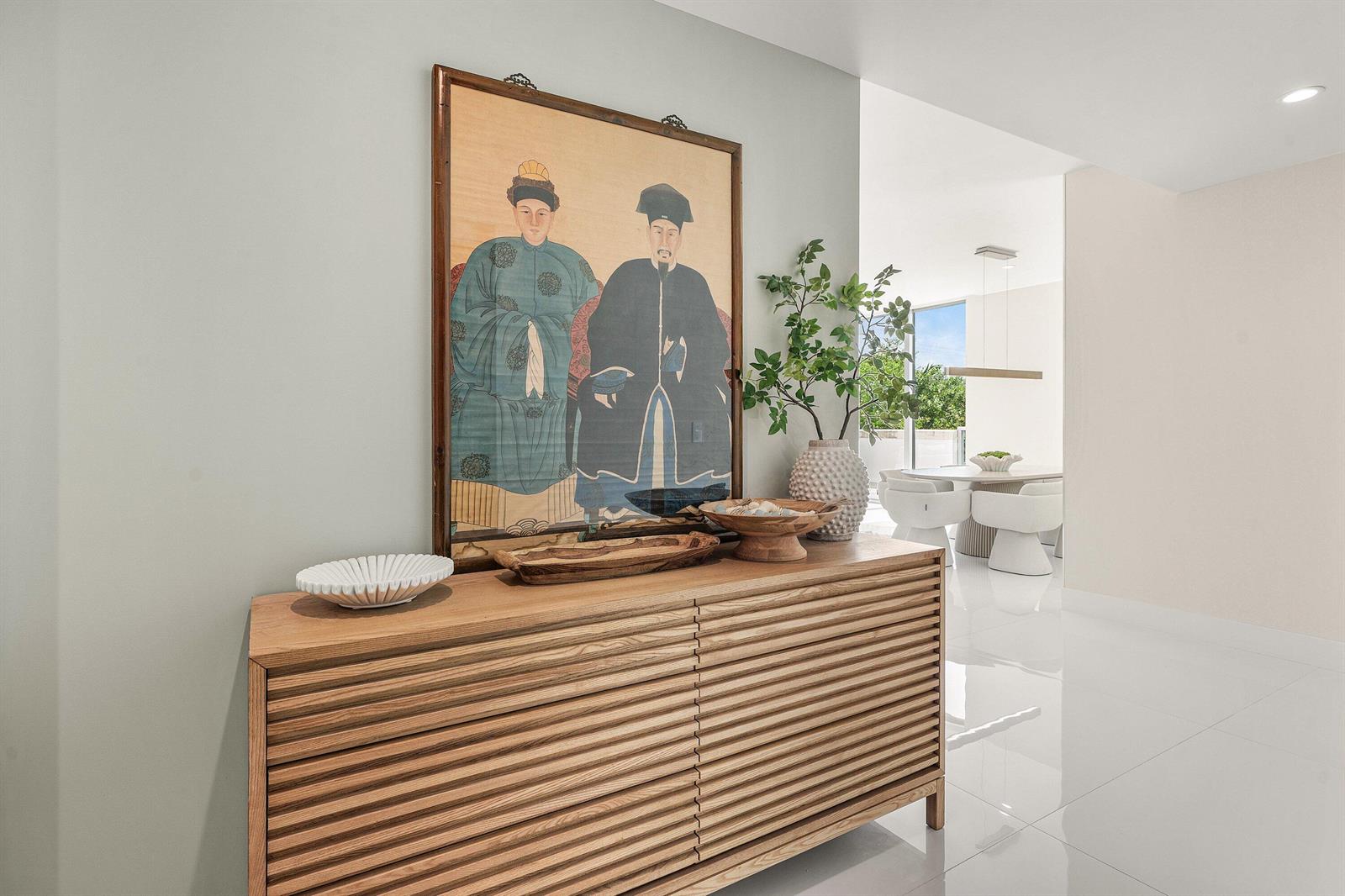 A wooden slatted console table sits against a light wall beneath a large portrait painting — 475 E Royal Palm Road # 206, Boca Raton FL 33432, BOCA RATON, FL