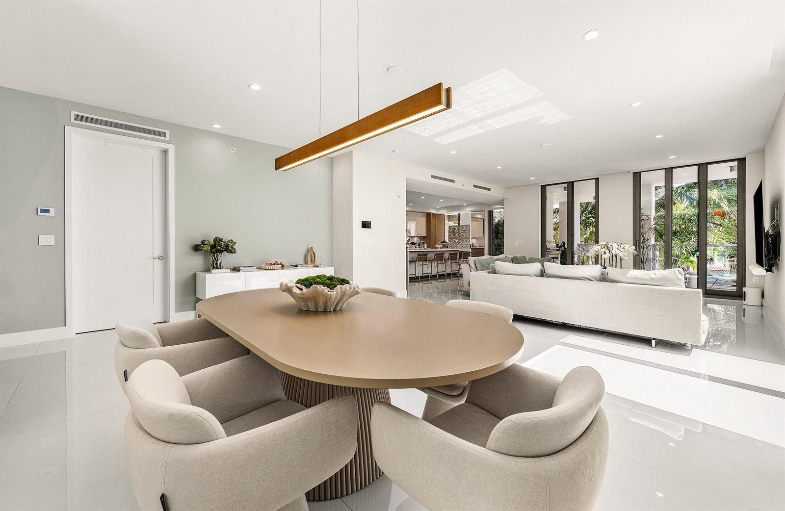 A dining area with an oval table and upholstered chairs opens into a bright living room — 475 E Royal Palm Road # 206, Boca Raton FL 33432, BOCA RATON, FL