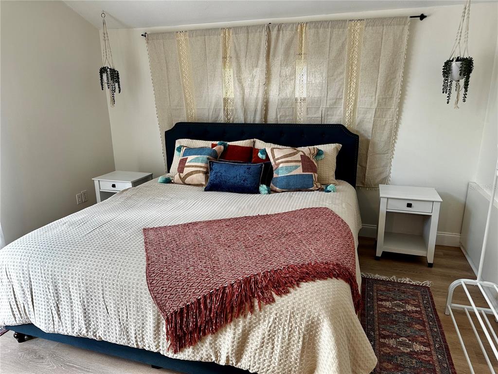 A bedroom features a blue upholstered bed, white nightstands, and a textured red throw blanket — 1222 E CRAWFORD STREET UNIT B, TAMPA, FL