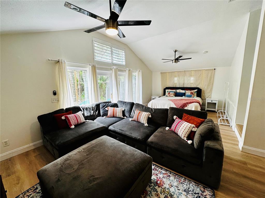 A bedroom features a large sectional sofa, a bed, and vaulted ceilings with two fans — 1222 E CRAWFORD STREET UNIT B, TAMPA, FL