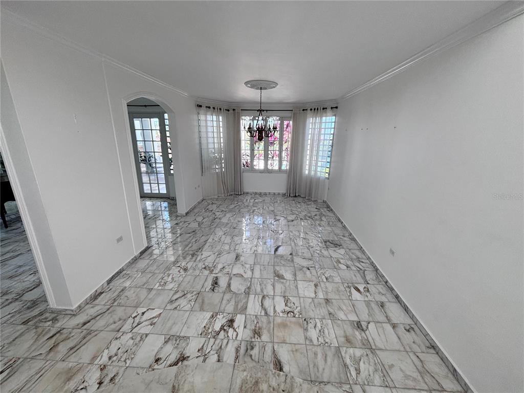 A dining room features white walls, a crystal chandelier, and polished marble tile flooring — Calle PITIERRE, SAN JUAN, PR
