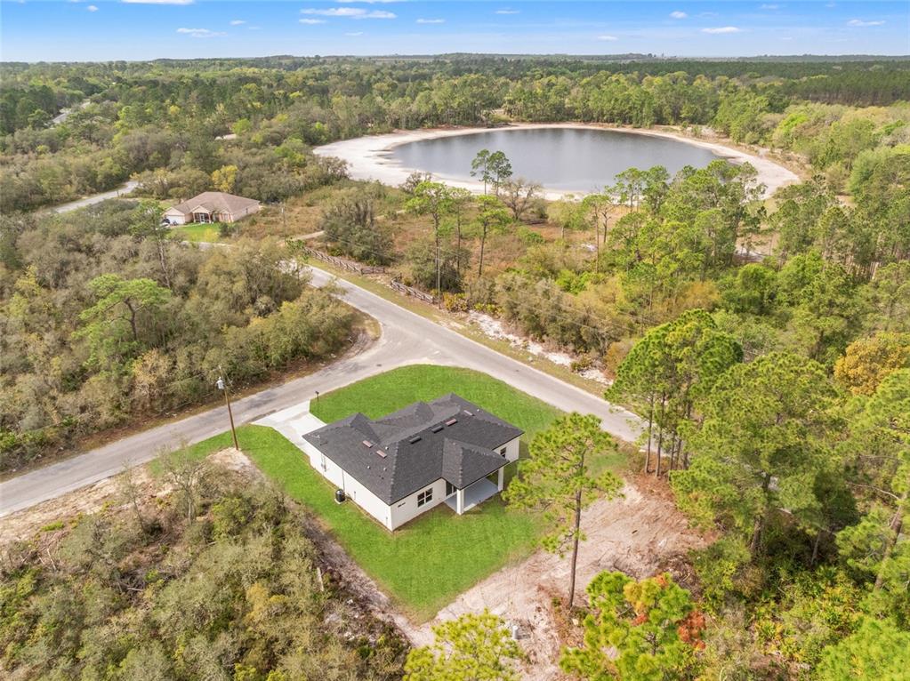 An aerial view shows a single-story house with a dark roof situated on a grassy lot — 33 FISHER PLACE, OCKLAWAHA, FL