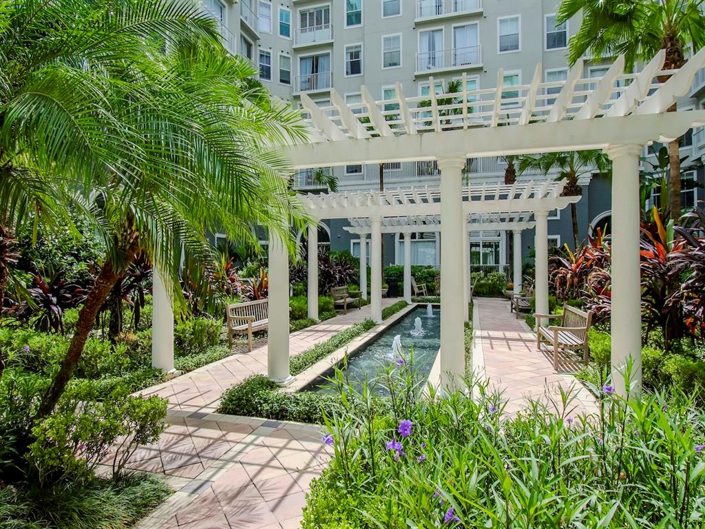 A white pergola covers a stone walkway and a narrow fountain in a courtyard garden — 700 S HARBOUR ISLAND BOULEVARD UNIT 245, TAMPA, FL