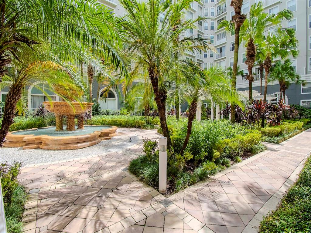 A stone fountain sits in a landscaped courtyard with palm trees and paved walkways — 700 S HARBOUR ISLAND BOULEVARD UNIT 245, TAMPA, FL