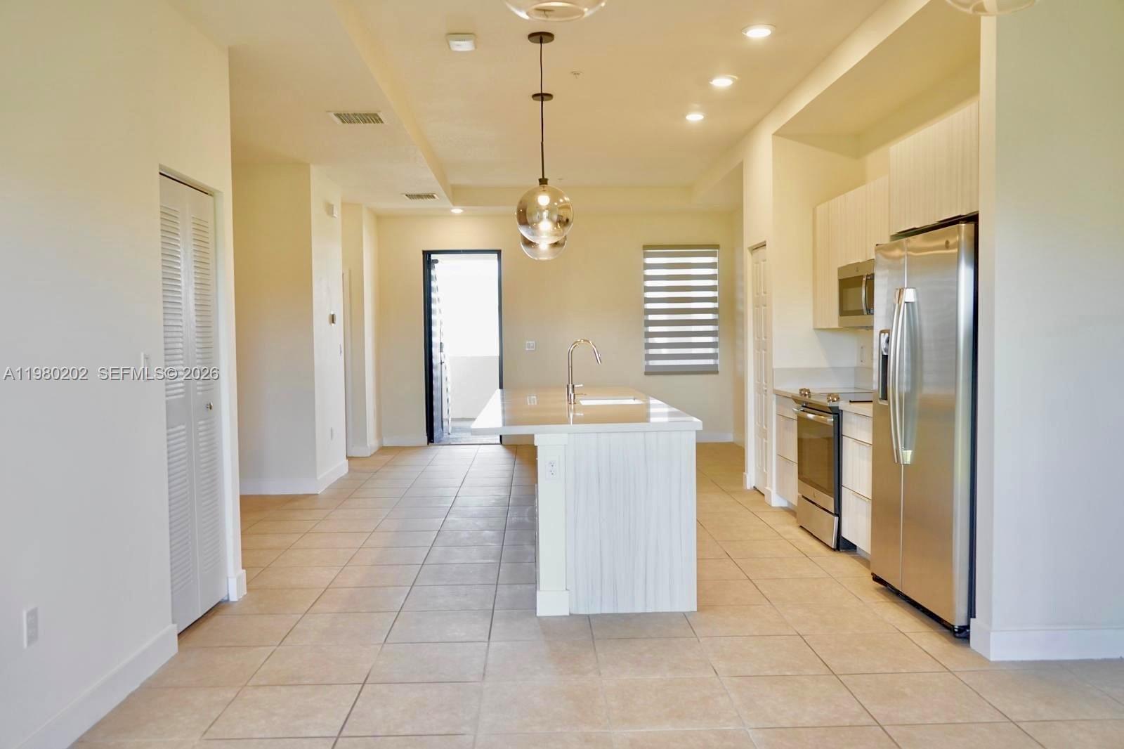 A modern kitchen features a central island, stainless steel appliances, and light-colored cabinetry — 7925 NW 104th Ave # 32, Doral FL 33178, DORAL, FL
