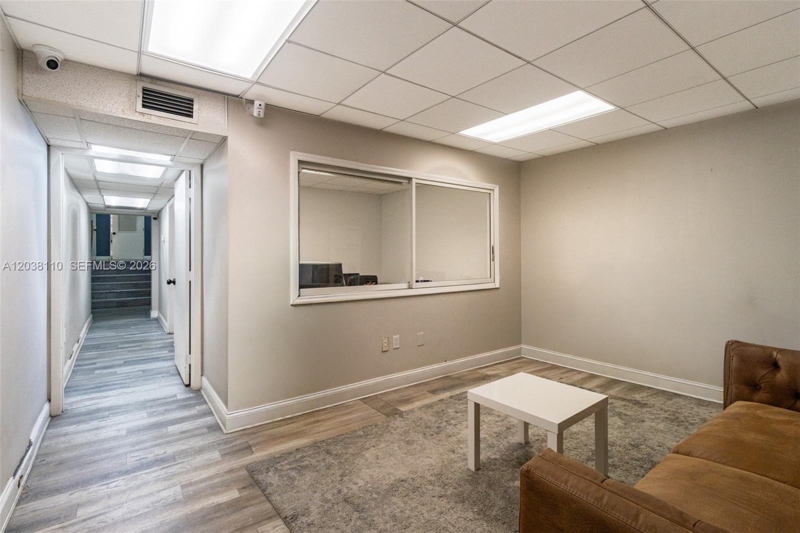A waiting room features a brown sofa, a white coffee table, and a sliding glass window — 3337 NW 74th Ave # 3337, Miami FL 33122, MIAMI, FL