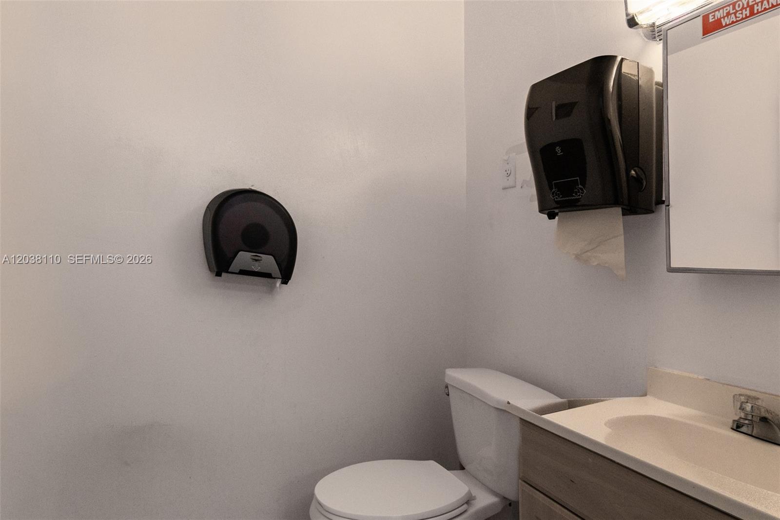 A small bathroom features a toilet, a vanity sink, and wall-mounted paper dispensers — 3337 NW 74th Ave # 3337, Miami FL 33122, MIAMI, FL