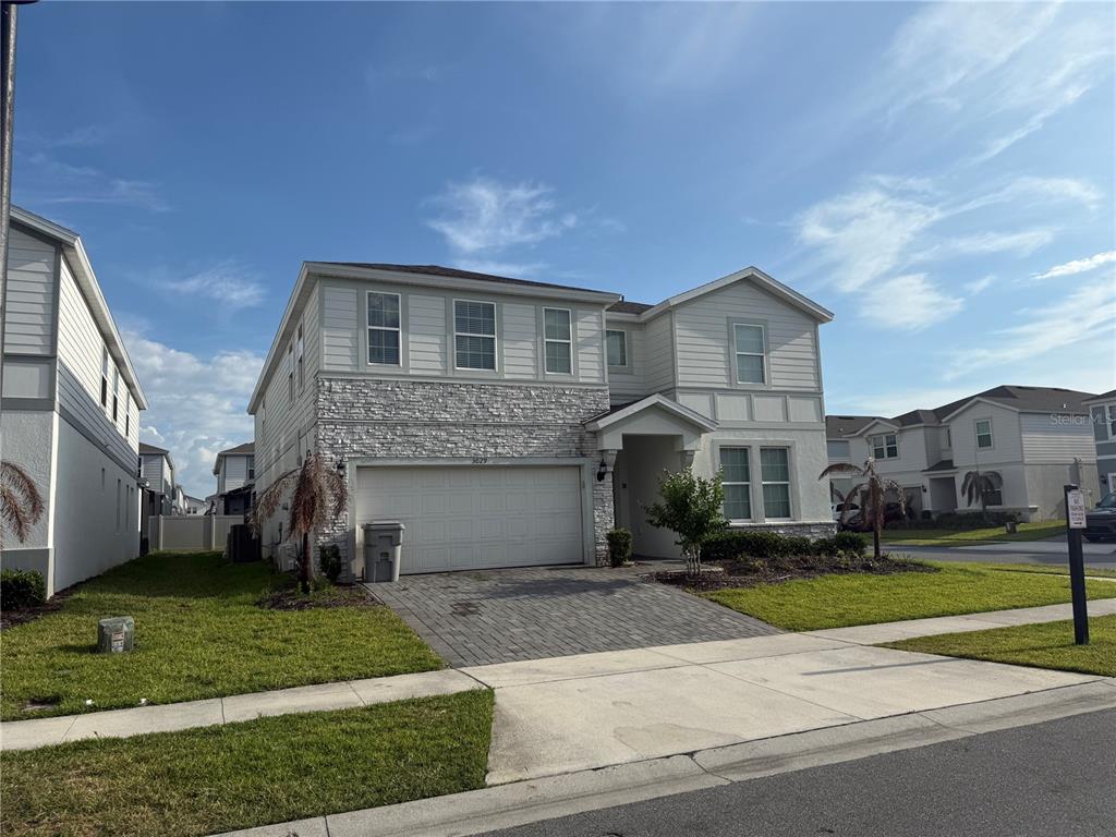A two-story suburban house features a stone facade, a two-car garage, and a paved driveway — 3029 MAHALO DRIVE, DAVENPORT, FL