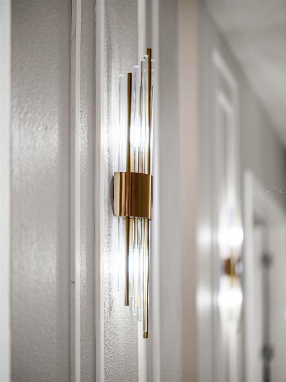 A modern gold and glass wall sconce is mounted on a white paneled wall — 3367 CANYON GRAND POINT, LONGWOOD, FL