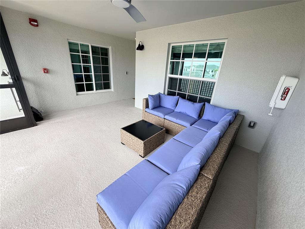 A covered patio features a large wicker sectional sofa with blue cushions and a coffee table — 15175 BLUFFTON LANE UNIT 724, PUNTA GORDA, FL