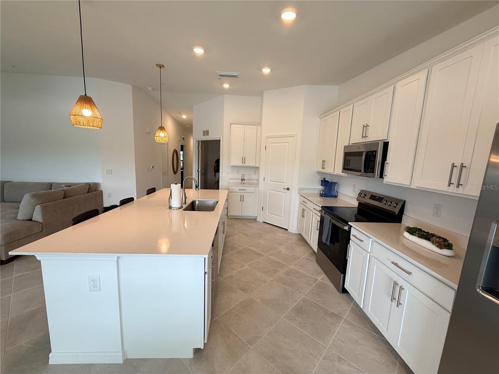 A kitchen features a large white island, stainless steel appliances, and white cabinetry — 15175 BLUFFTON LANE UNIT 724, PUNTA GORDA, FL