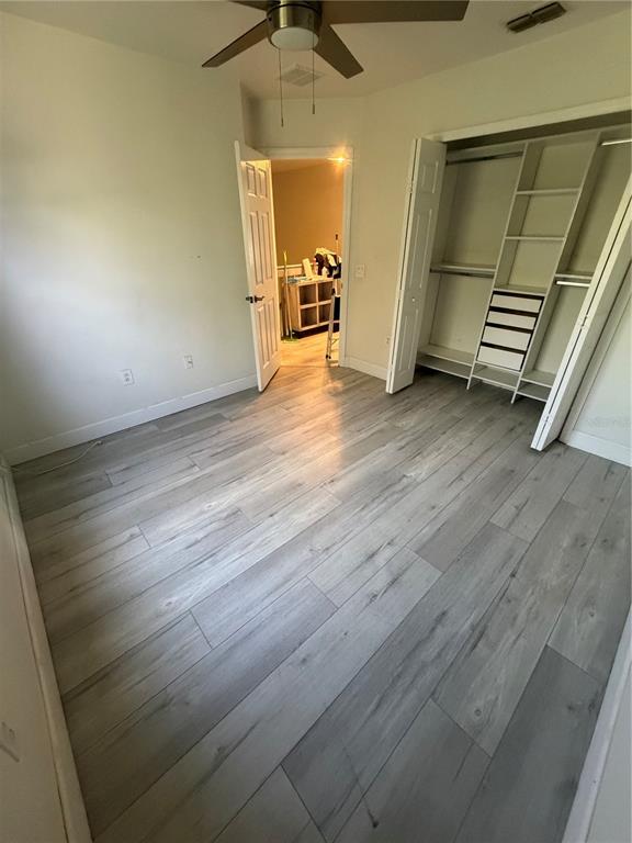 A bedroom features light wood-look flooring, a ceiling fan, and an open walk-in closet — 4048 VIOSCA PLACE, ORLANDO, FL