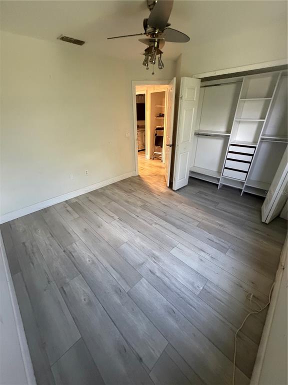 A bedroom with light-colored wood-look flooring, a ceiling fan, and a built-in closet system — 4048 VIOSCA PLACE, ORLANDO, FL