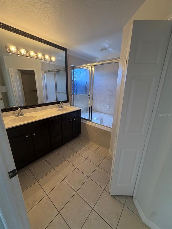 A bathroom features a double vanity with dark cabinets, a large mirror, and a shower-tub — 4048 VIOSCA PLACE, ORLANDO, FL