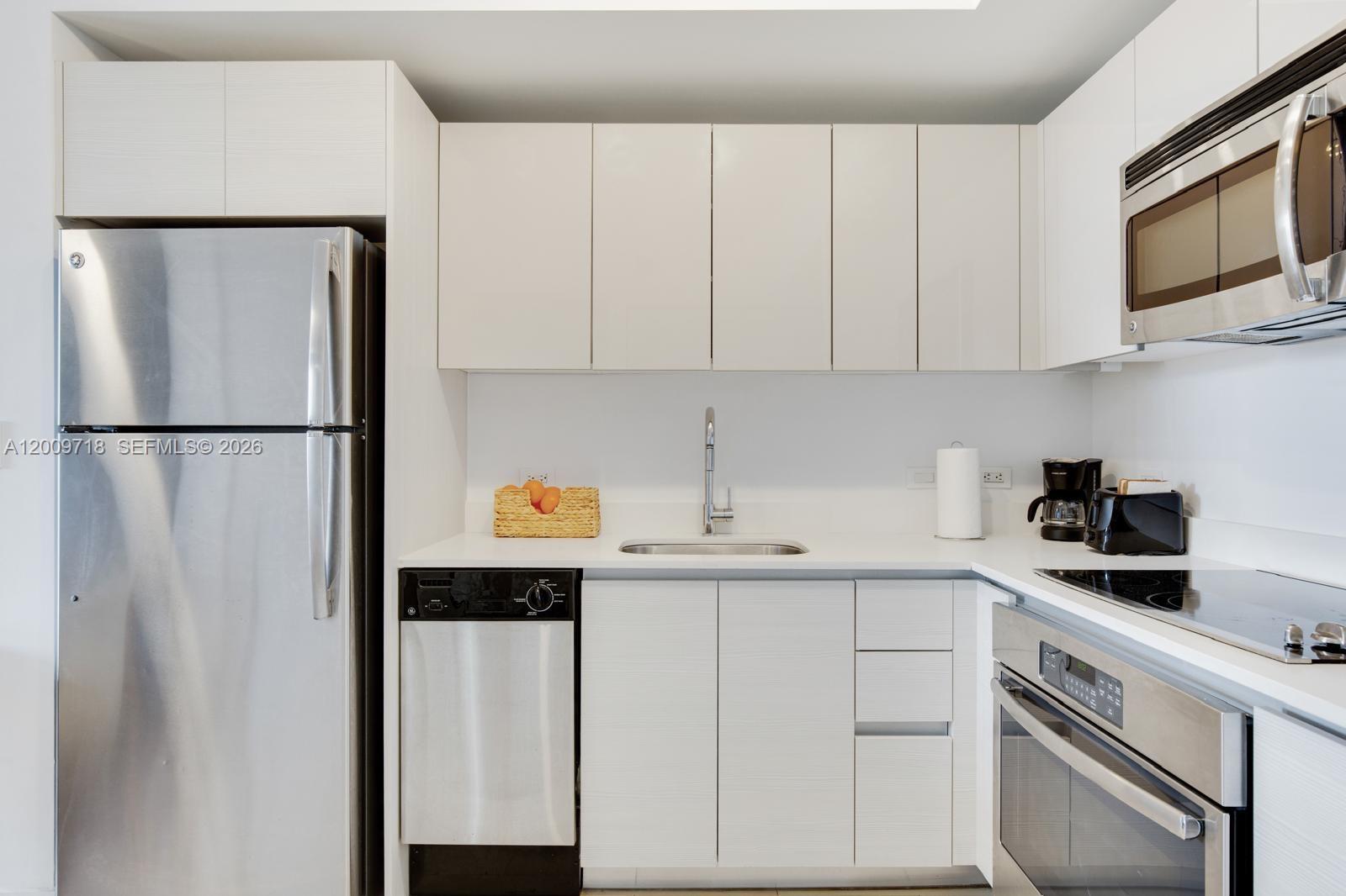 A modern kitchen features white cabinetry, stainless steel appliances, and a white countertop — 2602 E Hallandale Beach Blvd # R803, Hallandale Beach FL 33009, HALLANDALE BEACH, FL