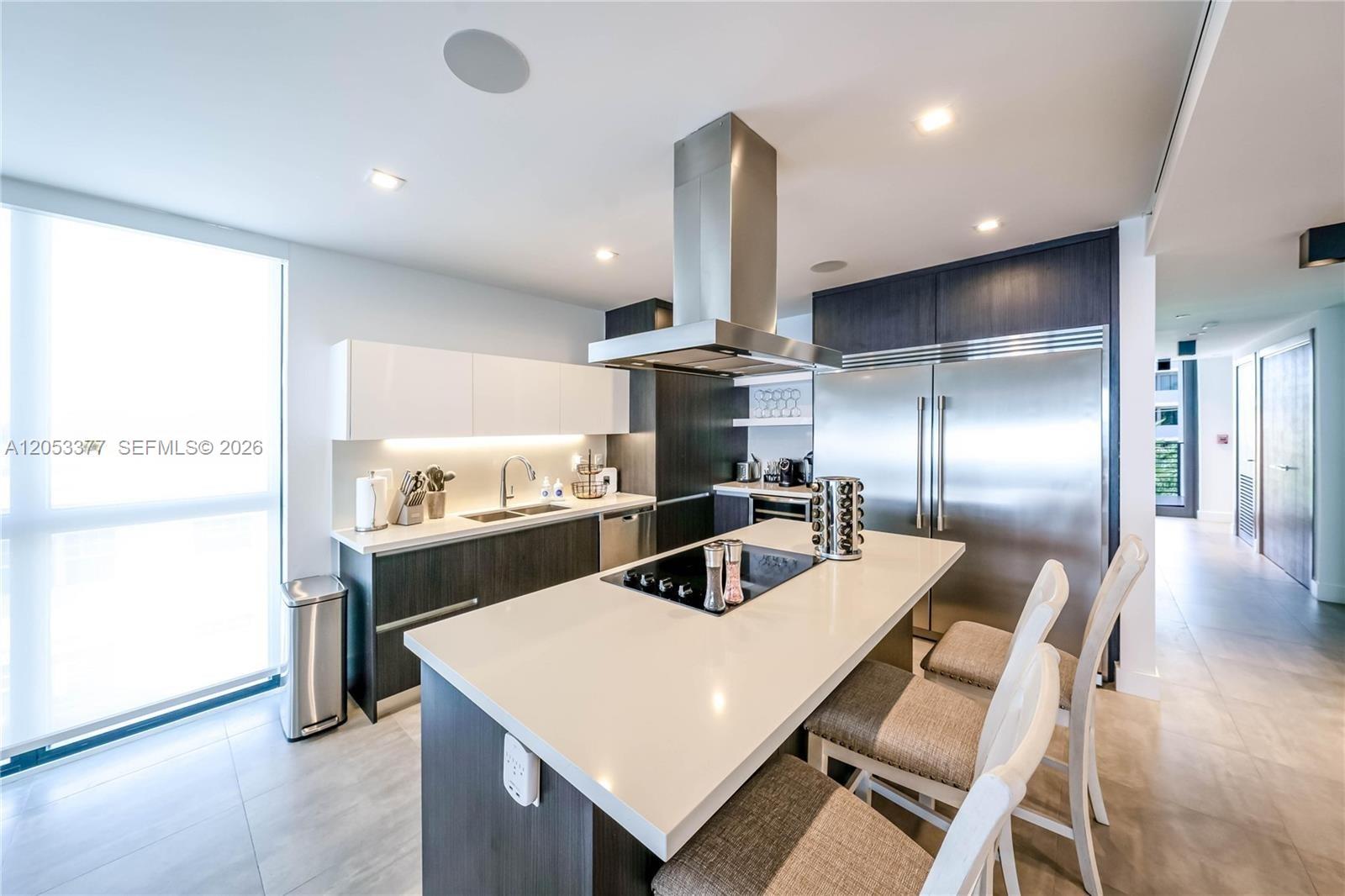 A modern kitchen features a central island with a cooktop, stainless steel appliances, and cabinetry — 1930 Bay Dr # 2, Miami Beach FL 33141, MIAMI BEACH, FL