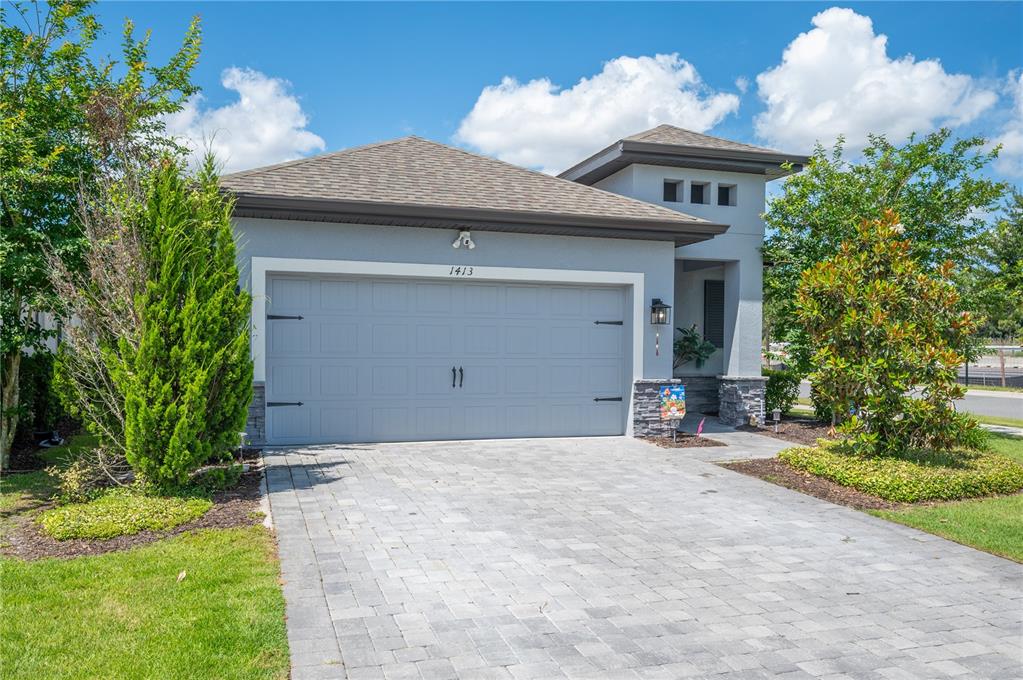 A gray single-story house with a two-car garage and a paved driveway — 1413 BELLAMY DRIVE, REUNION, FL