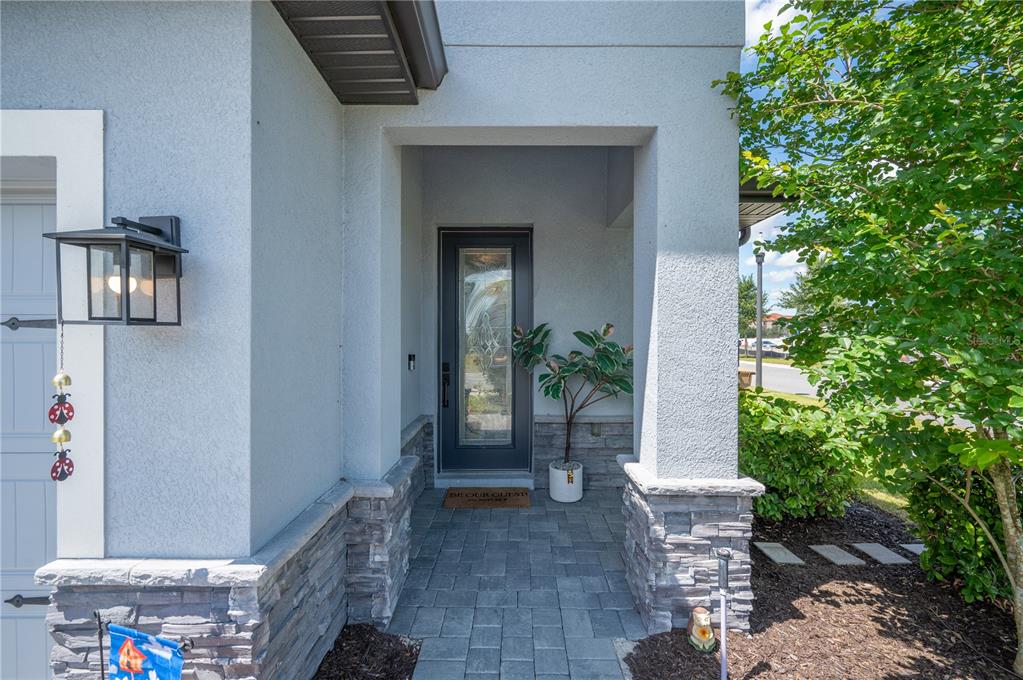 A front entryway features a gray door, stone veneer accents, and a paved walkway — 1413 BELLAMY DRIVE, REUNION, FL