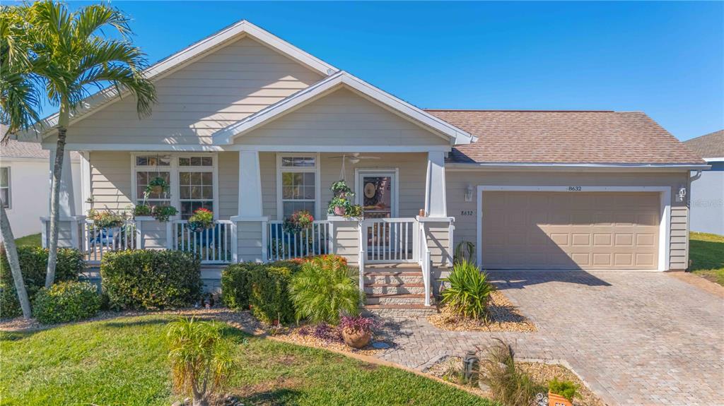 A single-story house with beige siding, a front porch, and an attached two-car garage — 8632 LAKE FRONT COURT, PUNTA GORDA, FL