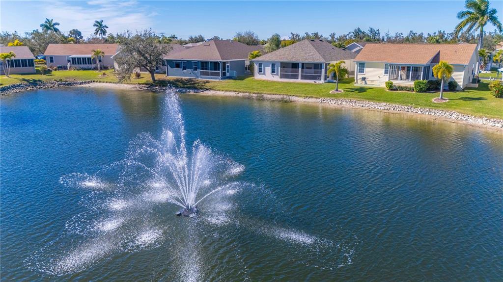 An aerial view of a lake with a fountain in front of several suburban houses — 8632 LAKE FRONT COURT, PUNTA GORDA, FL