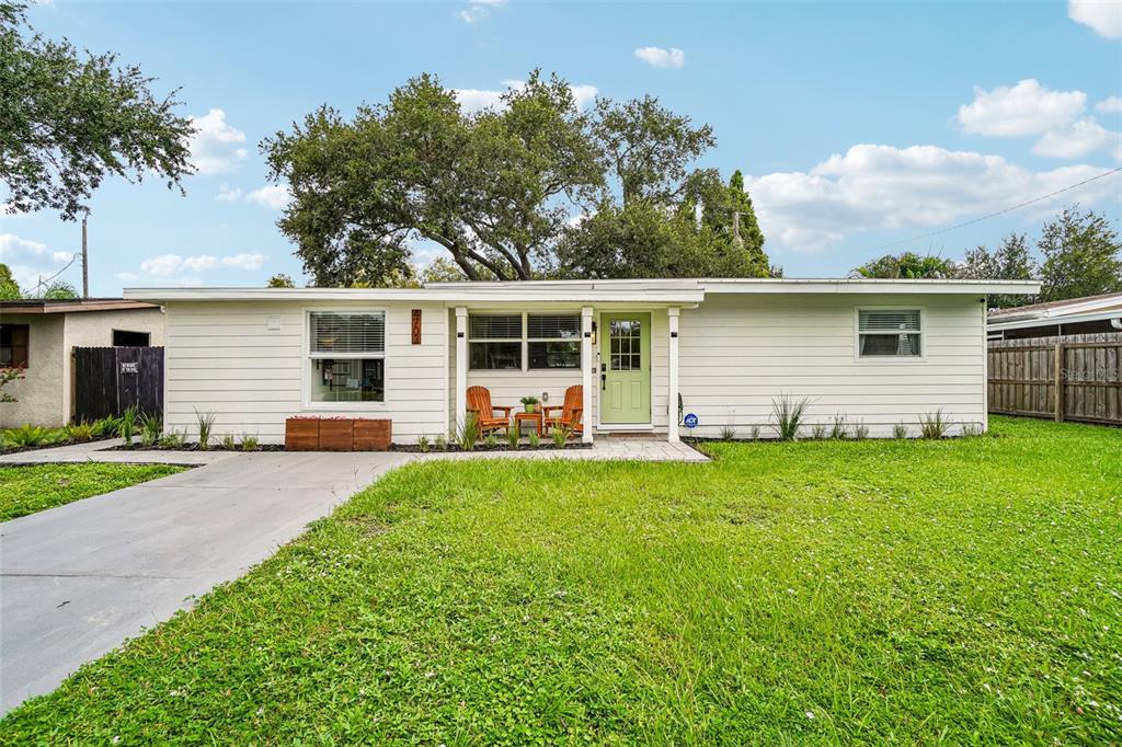 A single-story house with white horizontal siding, a light green front door, and a concrete driveway — 4703 W WALLACE AVENUE, TAMPA, FL
