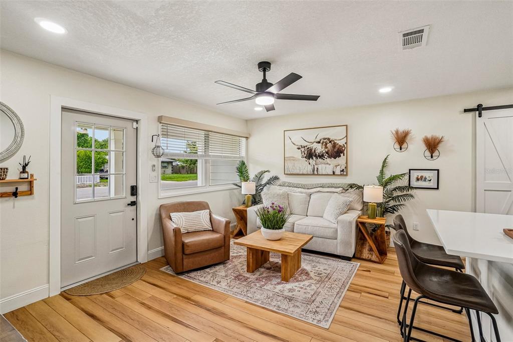 A living room with a sofa, leather armchair, coffee table, and light wood flooring — 4703 W WALLACE AVENUE, TAMPA, FL