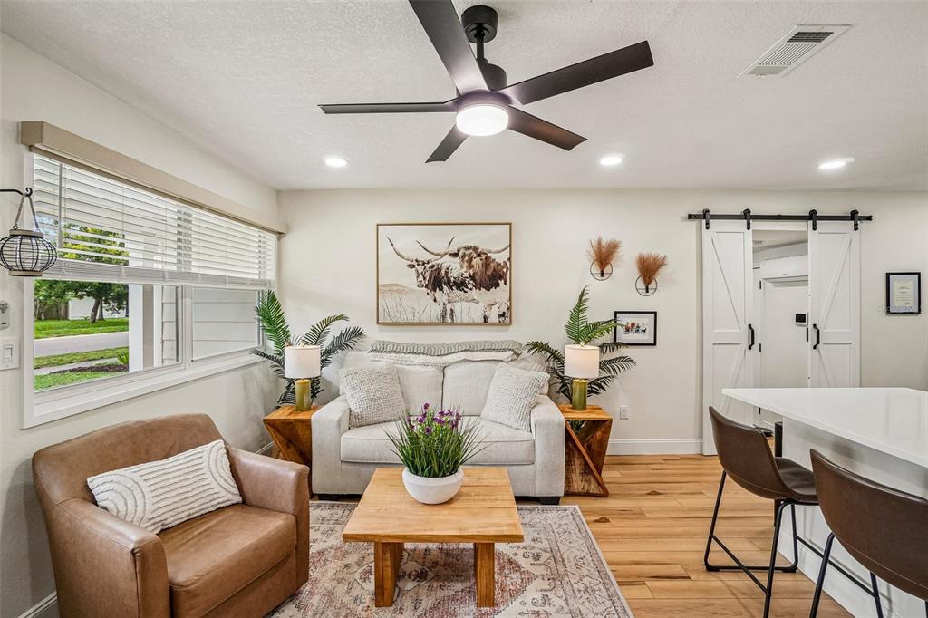 A living room features a sofa, leather armchair, wooden coffee table, and a ceiling fan — 4703 W WALLACE AVENUE, TAMPA, FL