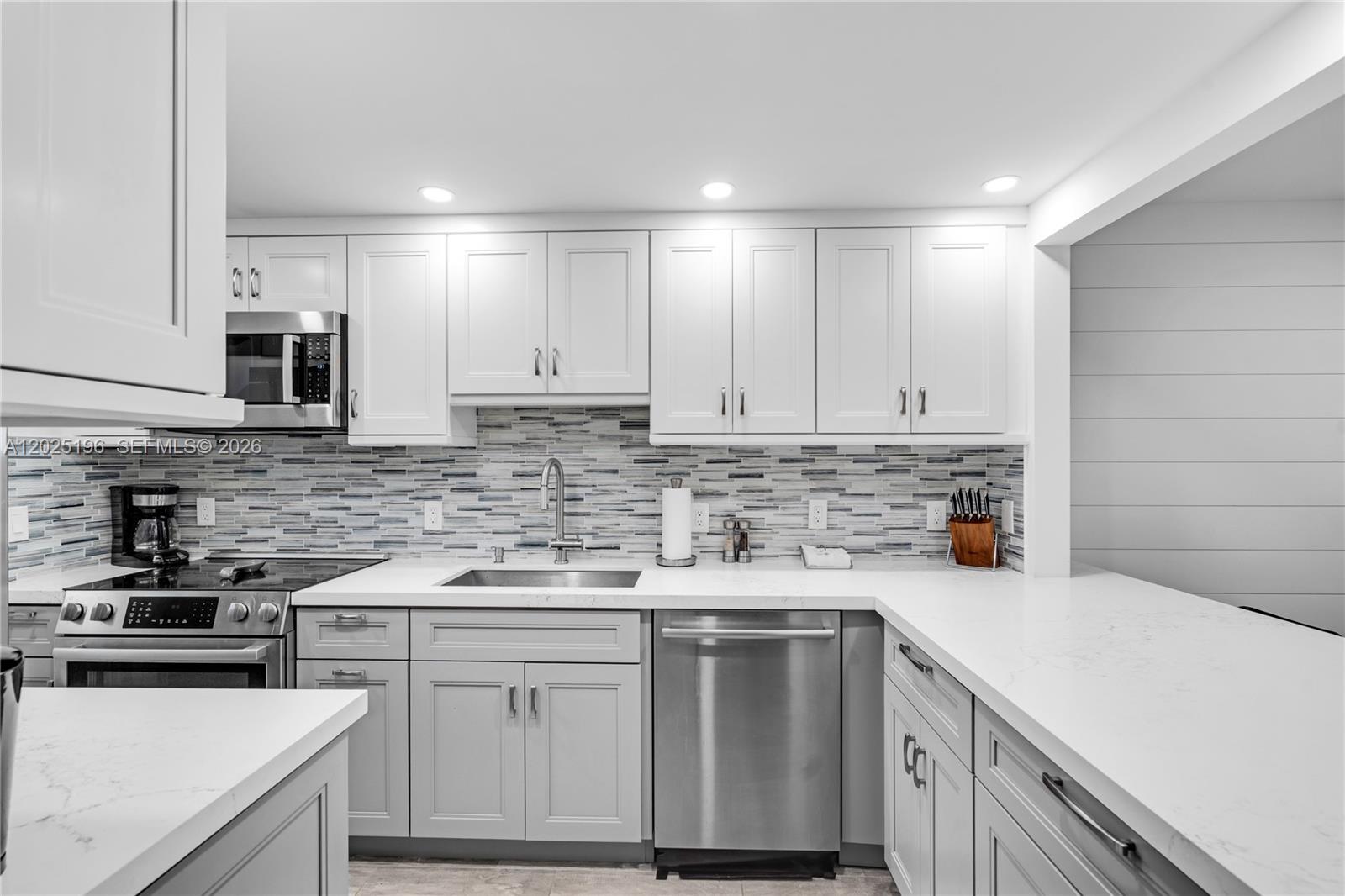 A kitchen features white cabinets, stainless steel appliances, a tiled backsplash, and white countertops — 4502 N Federal Hwy # 167H, Lighthouse Point FL 33064, LIGHTHOUSE POINT, FL
