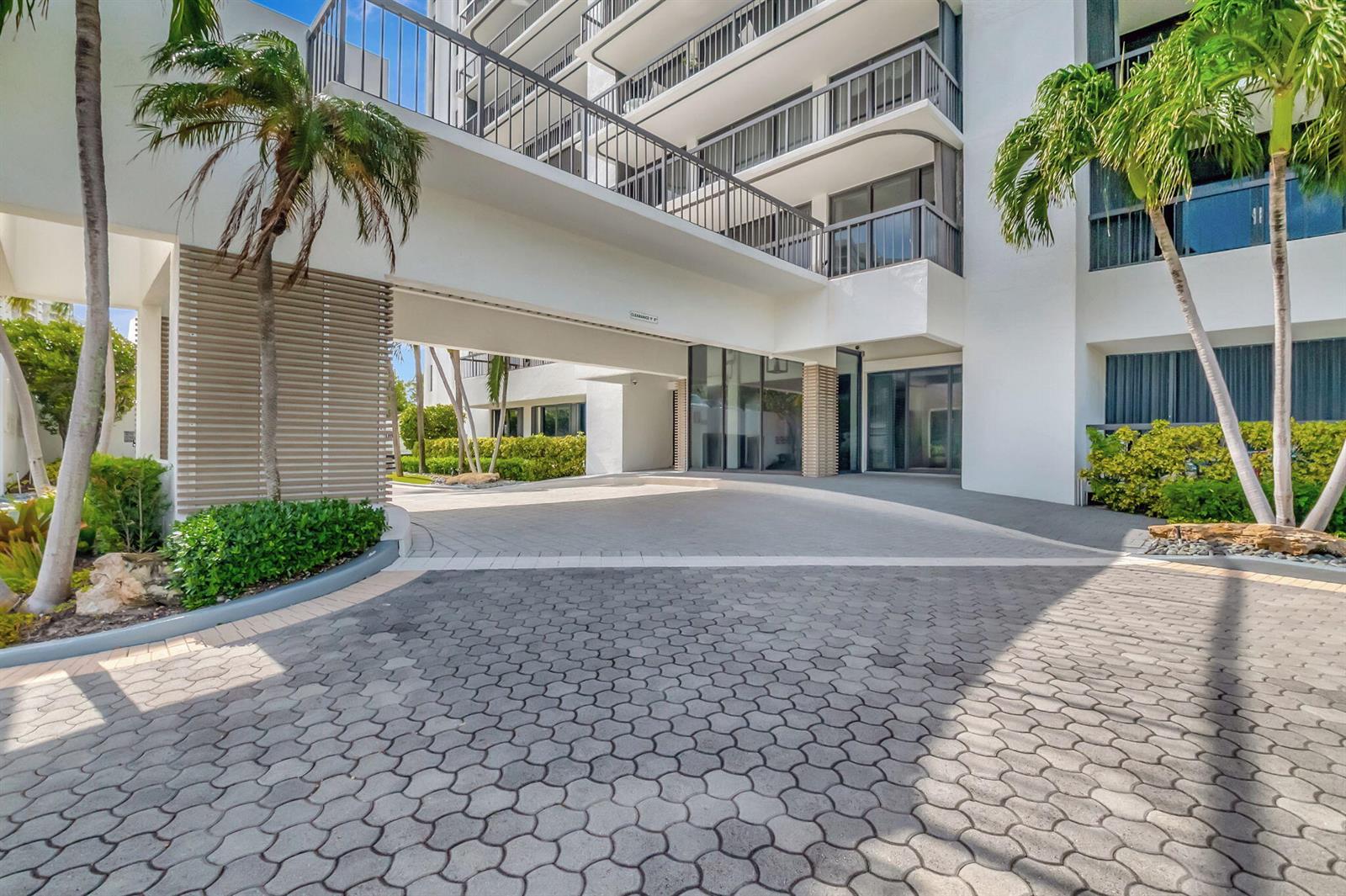 A paved driveway leads to the covered entrance of a multi-story white apartment building — 4748 S Ocean Boulevard # 203, Highland Beach FL 33487, HIGHLAND BEACH, FL