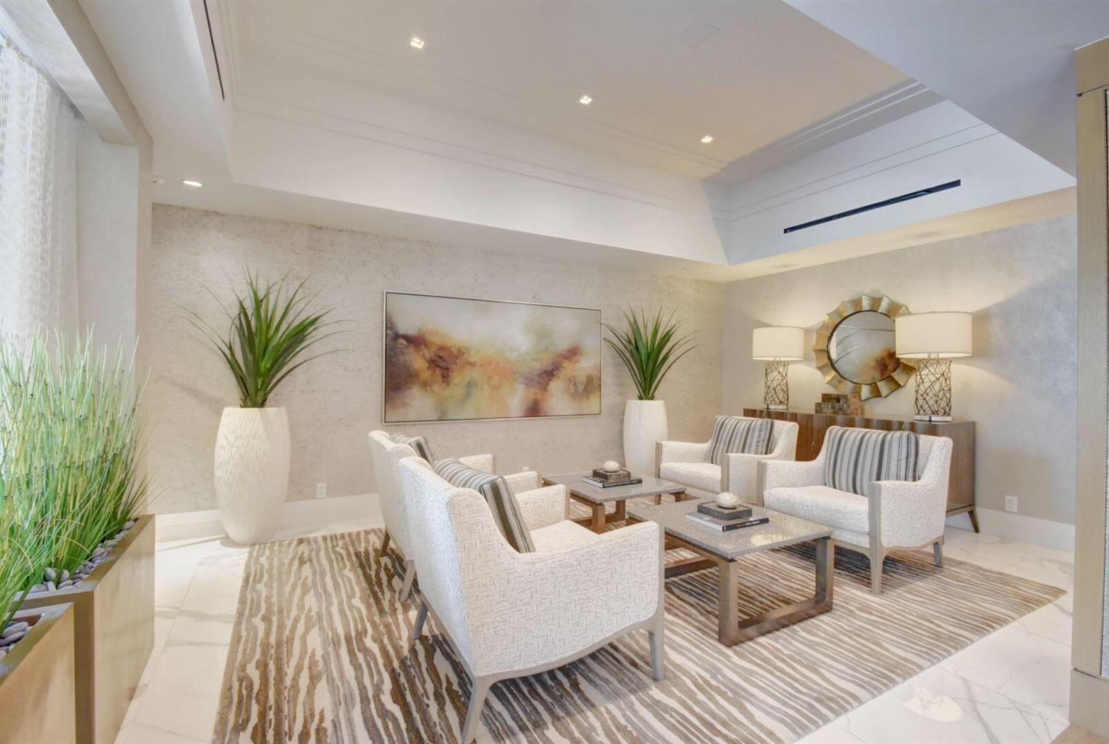 A modern living room features four white armchairs, two coffee tables, and a patterned rug — 4748 S Ocean Boulevard # 203, Highland Beach FL 33487, HIGHLAND BEACH, FL
