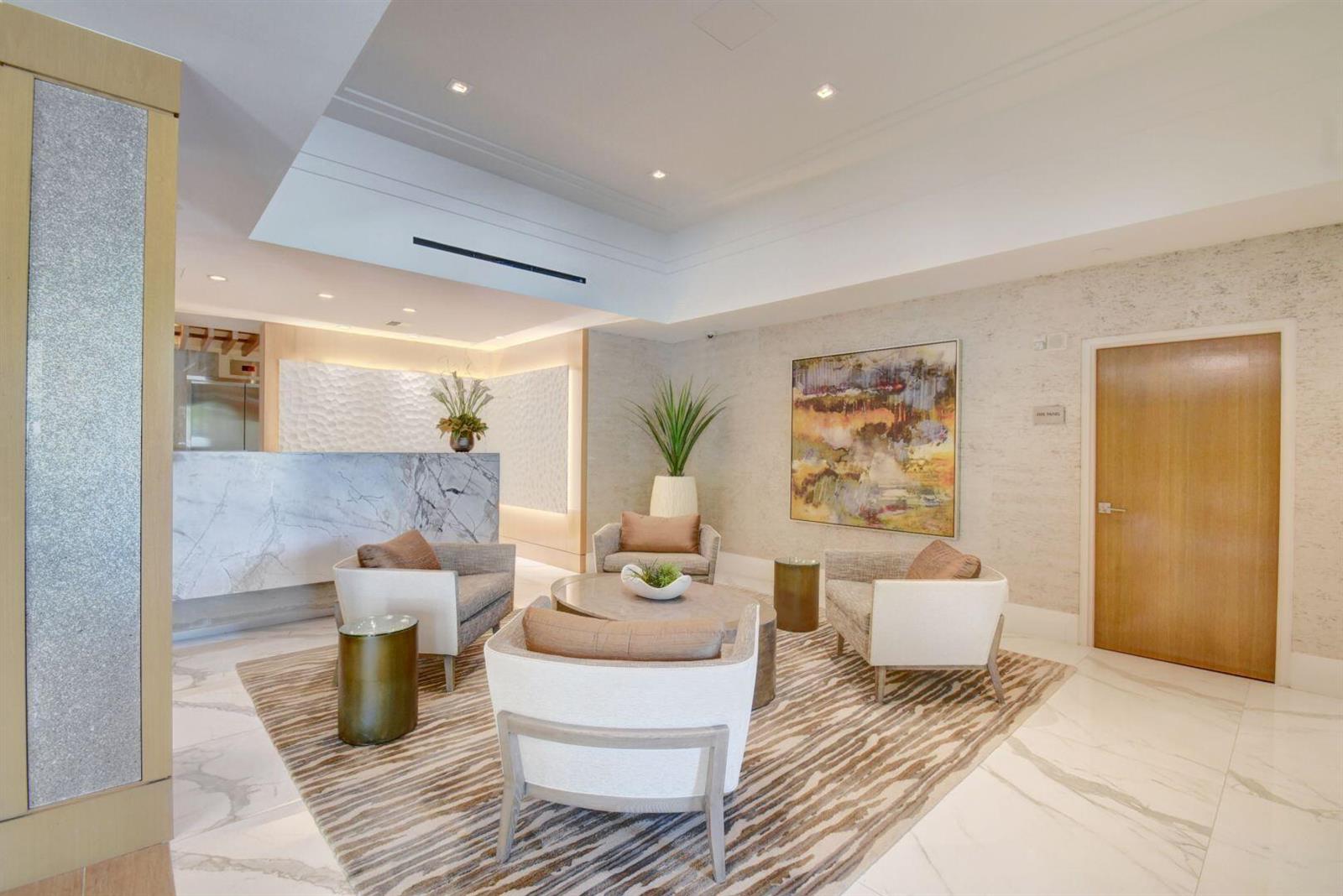 A modern lobby features marble flooring, a reception desk, and a seating area with armchairs — 4748 S Ocean Boulevard # 203, Highland Beach FL 33487, HIGHLAND BEACH, FL