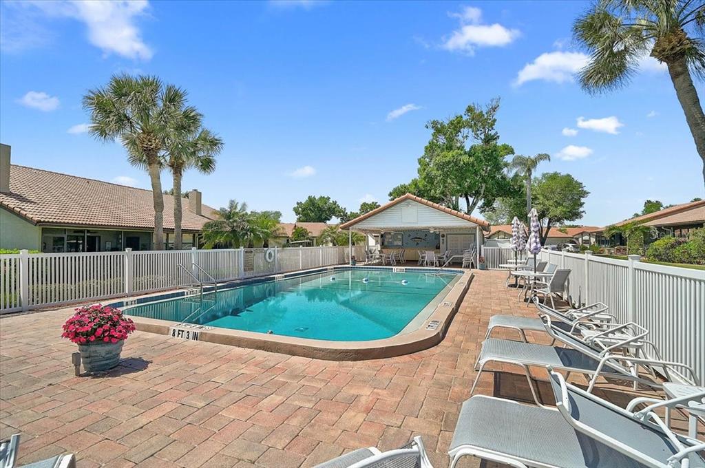 A rectangular outdoor swimming pool is surrounded by a brick patio and lounge chairs — 892 COUNTRY CLUB CIRCLE UNIT 50, VENICE, FL