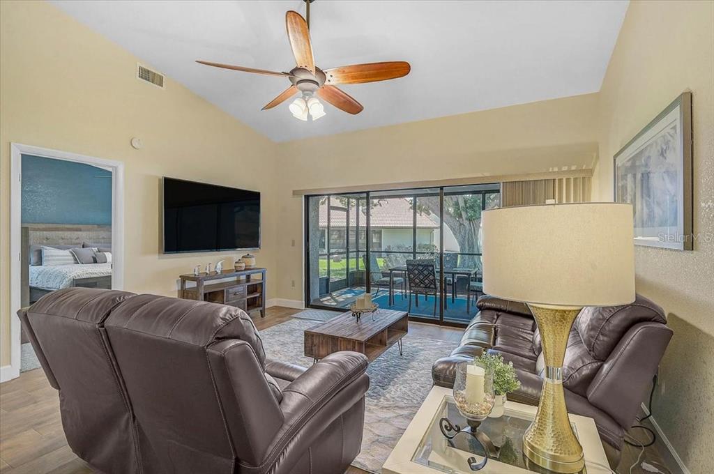 A living room with a ceiling fan, leather furniture, and sliding doors opening to a patio — 892 COUNTRY CLUB CIRCLE UNIT 50, VENICE, FL