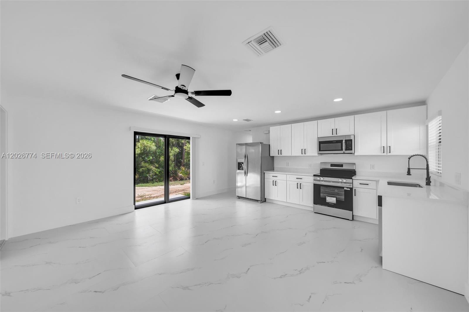 A modern kitchen and dining area features white cabinets, stainless steel appliances, and marble-look flooring — 4984 Fairway Ct # 4984, Lehigh Acres FL 33171, LEHIGH ACRES, FL