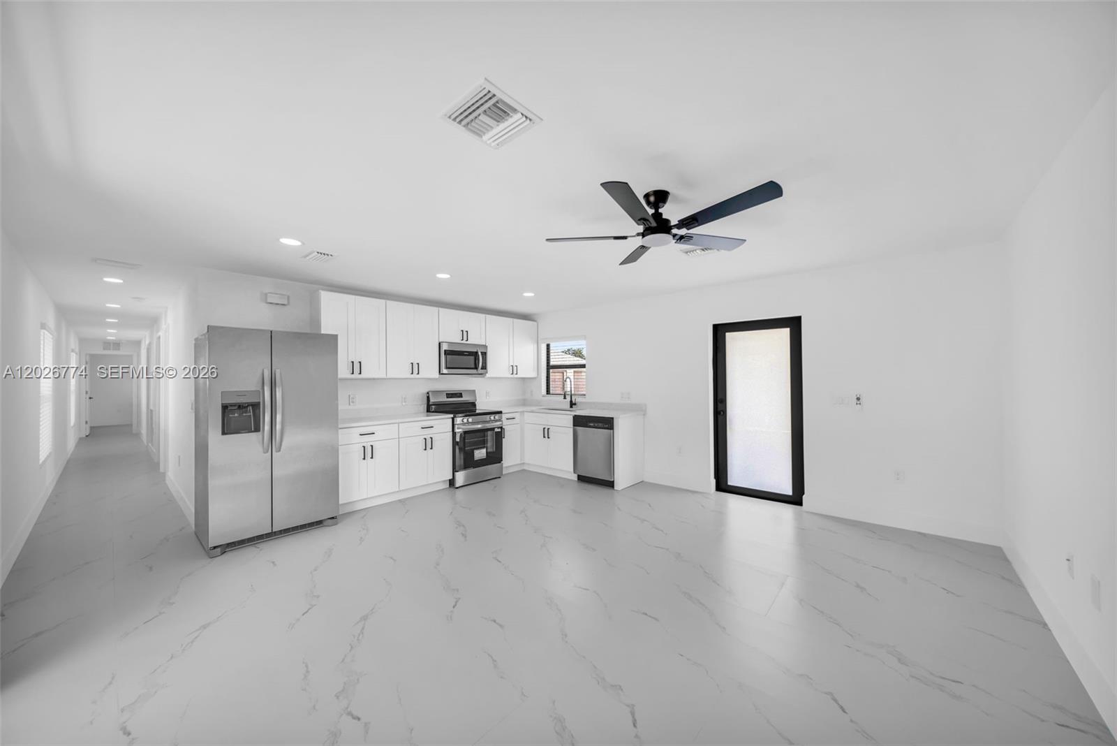 A modern kitchen features white cabinets, stainless steel appliances, and light gray marble-patterned tile flooring — 4984 Fairway Ct # 4984, Lehigh Acres FL 33171, LEHIGH ACRES, FL