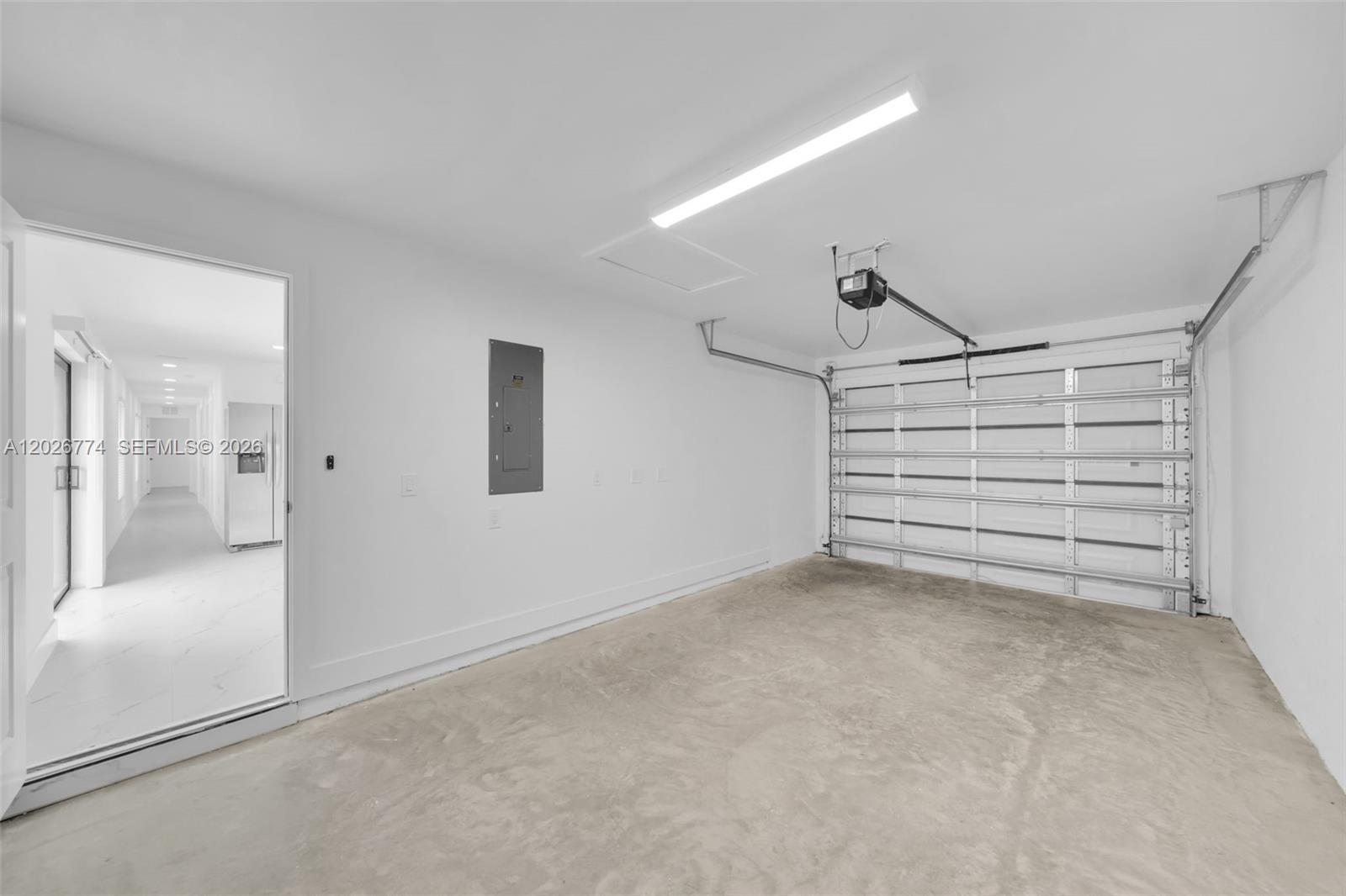 A clean, white-walled garage features a concrete floor, a metal door, and an electrical panel — 4984 Fairway Ct # 4984, Lehigh Acres FL 33171, LEHIGH ACRES, FL