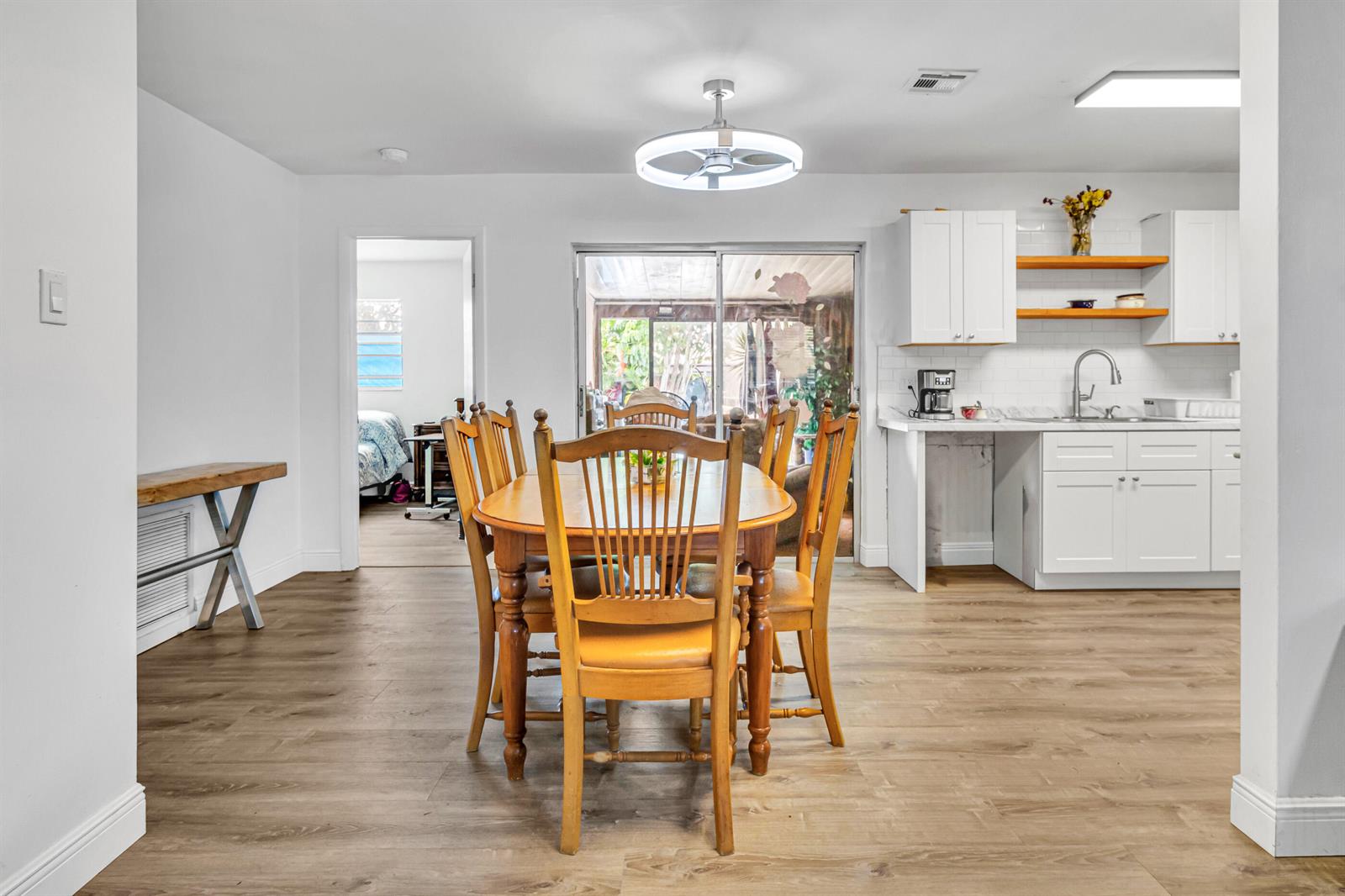 A dining area with a wooden table and chairs sits adjacent to a white kitchen — 4469 Brandon Drive, Delray Beach FL 33445, DELRAY BEACH, FL