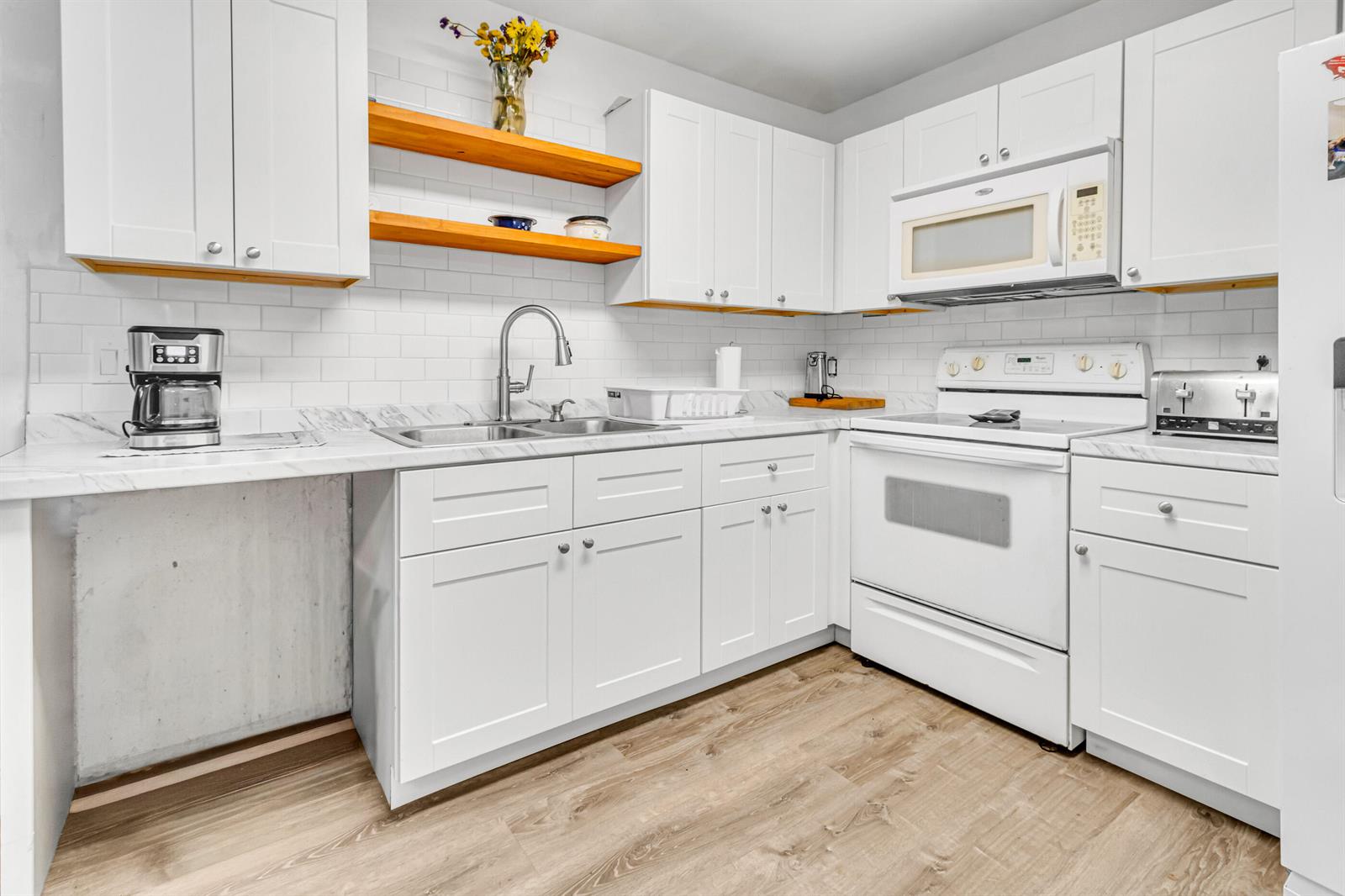 A kitchen features white cabinets, marble-look countertops, subway tile backsplash, and open wooden shelving — 4469 Brandon Drive, Delray Beach FL 33445, DELRAY BEACH, FL