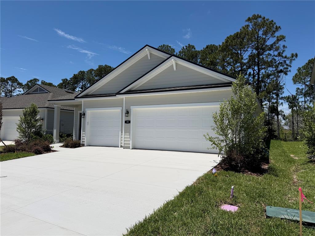 A light-colored house exterior features a two-car garage and a single-car garage — 35 PERSEUS AVENUE, FLAGLER BEACH, FL