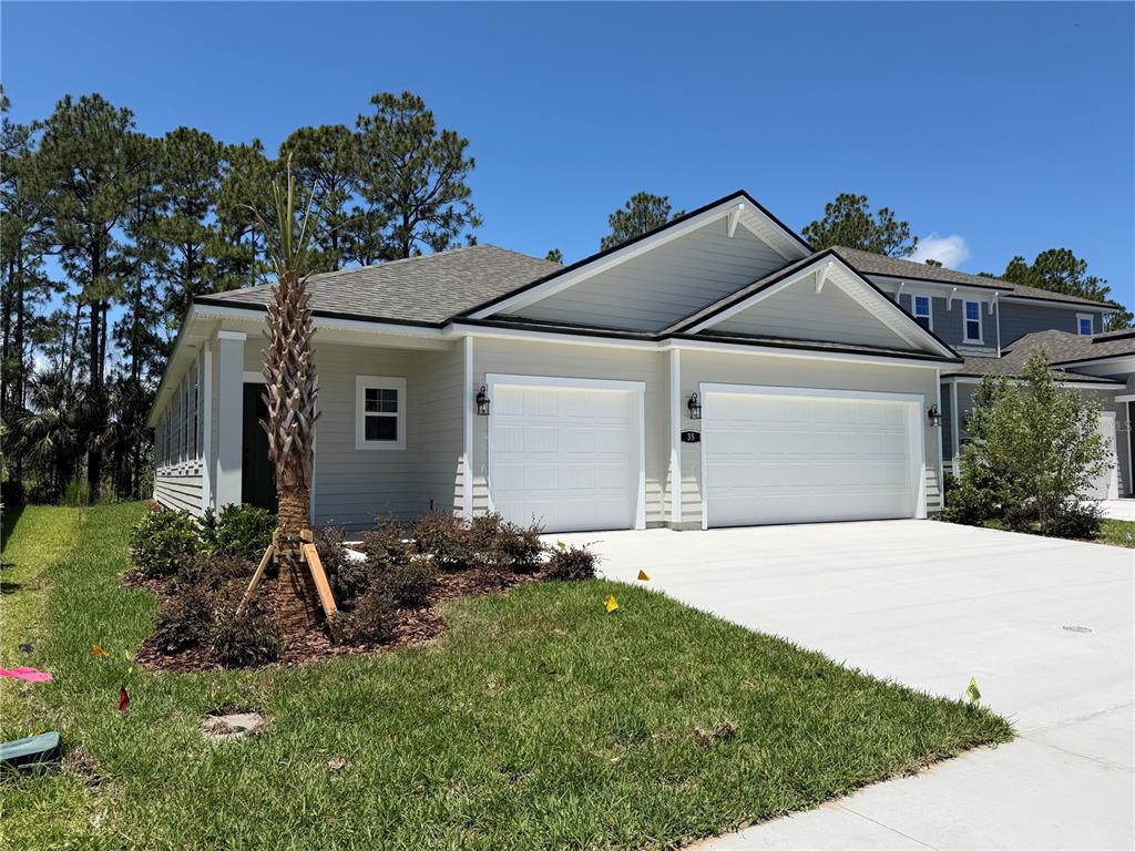 A light-colored single-story house features a two-car garage and a small palm tree — 35 PERSEUS AVENUE, FLAGLER BEACH, FL