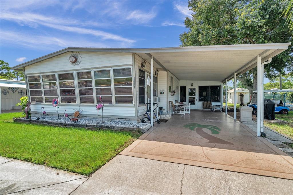 A single-story manufactured home with a white exterior, a carport, and a front lawn — 6524 ROOSEVELT DRIVE, PORT RICHEY, FL