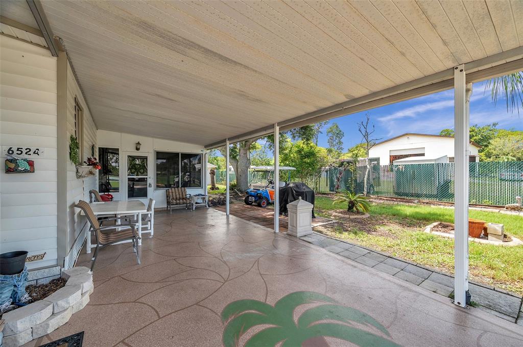A covered patio features a decorative concrete floor, outdoor furniture, and a view of the yard — 6524 ROOSEVELT DRIVE, PORT RICHEY, FL
