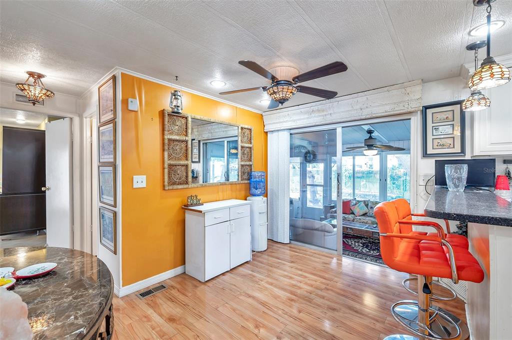 A dining area with orange walls, wood-look flooring, a ceiling fan, and a sliding glass door — 6524 ROOSEVELT DRIVE, PORT RICHEY, FL